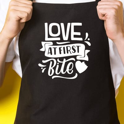 Zwart keukenschort / BBQ-schort met tekst | Love at first Bite | Katoen - One size - Verstelbaar - Wasbaar - Cadeau voor hem - Vaderdag - Gratis verzending - Cadeau voor Kerst & sinterklaas | Incl. 2 jaar garantie