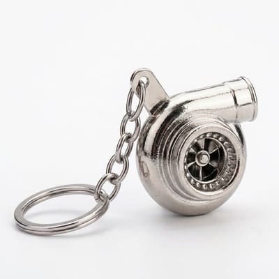 Zilverachtige sleutelhanger turbocharger vorm met metalen sleutelring en korte schakelketting, sleutelhanger voor heren en dames, compact accessoire met mechanisch ontwerp en glanzend industrieel detail