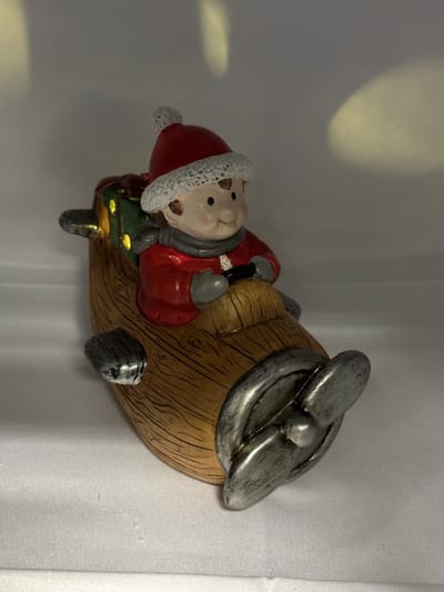 Kerstbeeldje jongen in bruin vliegtuig met LED - bruin+rood & groen cadeau - polyresin - 13 cm hoog x 16 cm x 5 cm – Kerstdecoratie