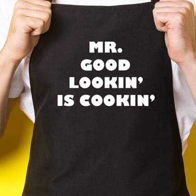 Zwart keukenschort / BBQ-schort met tekst | Mr. Good Lookin is Cookin | Katoen - One size - Verstelbaar - Wasbaar - Cadeau voor hem - Vaderdag - Gratis verzending - Cadeau voor Kerst & sinterklaas | Incl. 2 jaar garantie