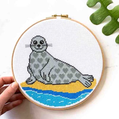 Studio Koekoek - Zeehond borduurpakket - zomers thema strand kruissteek borduurpakket - telpatroon - inclusief houten ring - gemaakt in Amsterdam