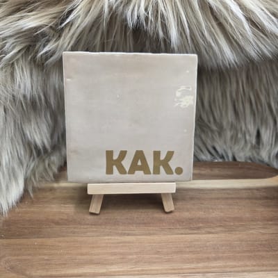 Robuust Wenstegeltje “KAK.” – 10X10CM – Humoristisch Cadeau – Trendy nu – Cadeau voor Nieuwe Woning, Housewarming of voor vriend(in) – Sfeervol en Persoonlijk – Zomaar - Wc decoratie – Decoratief Tegeltje met Standaard – Cadeau Idee