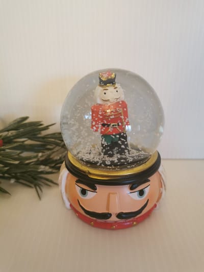 Sneeuwbol Notenkraker met rode jas op sokkel met gezicht van de notenkraker