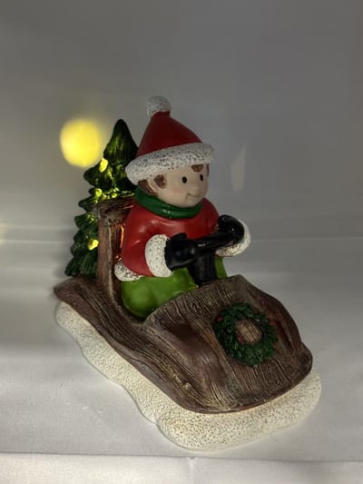 Kerstbeeldje jongen in rode auto met LED - bruin+rood & groene kerstboom - polyresin - 12 cm hoog x 16 cm x 8 cm – Kerstdecoratie
