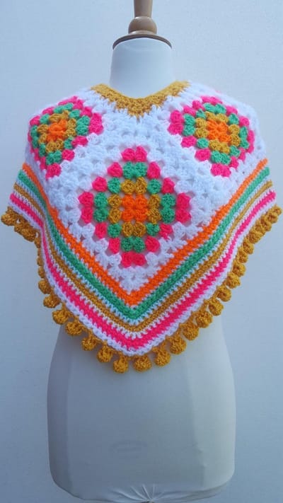 Kinder poncho gehaakt in felroze, groen, oranje, wit, geel met glinsterdraad en bolletjesrand handgemaakt