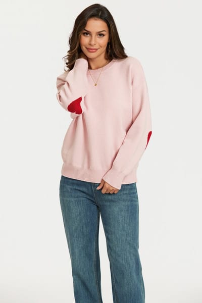 Gebreide trui in roze met rood hartpatroon op de mouwen