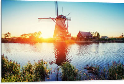 WallClassics - Dibond - Zonlicht langs Hollandse Molen aan het Water - 105x70 cm Foto op Aluminium (Met Ophangsysteem)