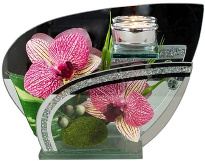 Glazen decoratie met donkerroze bloemen en theelichtje.