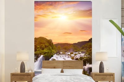 Behang - Fotobehang Waterval - Landschap - Zon - Wolken - Zonsondergang - Breedte 180 cm x hoogte 280 cm