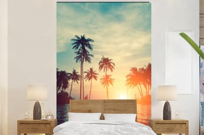Behang - Fotobehang Zee - Zonsondergang - Palmboom - Wolken - Breedte 195 cm x hoogte 300 cm