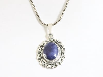 Bewerkte zilveren hanger met blauwe saffier aan ketting