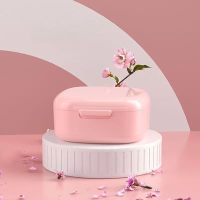 Twee opbergdozen voor kunstgebitten met gaas, een doos voor orthodontische apparaten, een prothesehouder, een doos voor spalken, een reinigingsdoos,roze