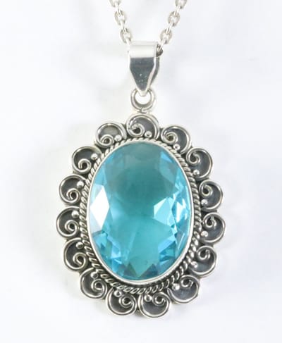 Grote bewerkte zilveren hanger met blauwe topaas aan ketting