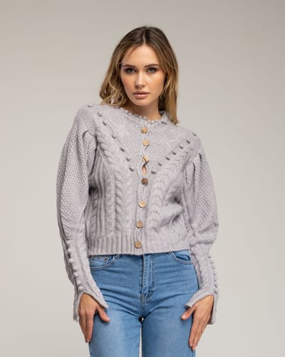 Gehaakt vest met pompons en bloemendetails.