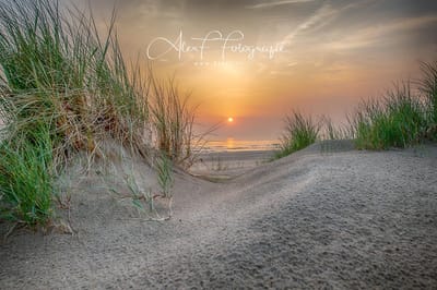 Schilderij | Foto op Canvas,  Schitterende oranje zonsondergang vanuit het duin  (120x80cm)