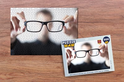 Puzzel Een close-up man met bril die de bril toont aan de camera. - Legpuzzel - Puzzel 500 stukjes