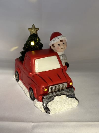 Kerstbeeldje jongen in rode sneeuw auto met LED - groene Kerstboom - polyresin - 12 cm hoog x 16 cm x 8 cm – Kerstdecoratie