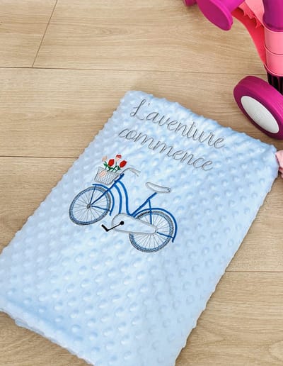 Couverture bleue pour bébé avec un vélo et une dédicace en français brodée/Blue baby blanket with a bicycle and a dedication in French embroidered 95 x 120 cm