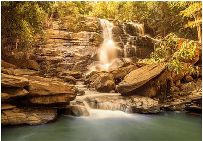 Fotobehangkoning - Behang - Vliesbehang - Fotobehang Waterval in de Zon - 150 x 105 cm