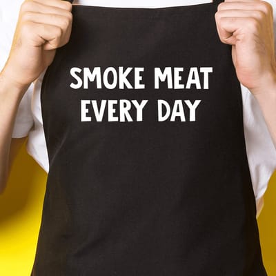 Zwart keukenschort / BBQ-schort met tekst | Smoke meat every day | Katoen - One size - Verstelbaar - Wasbaar - Cadeau voor hem - Vaderdag - Gratis verzending - Cadeau voor Kerst & sinterklaas | Incl. 2 jaar garantie