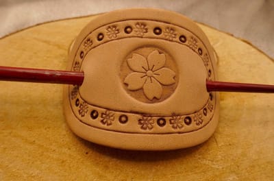 Leren beige haarspeld bloem in bloemenrand - lederen bloemen haarspeld - bloemetjes haarspeld - beige haarspeld met kleine bloemetjes in rand in het midden een grote bloem - sierlijke haaraccessoires - vrouwen haarsieraad