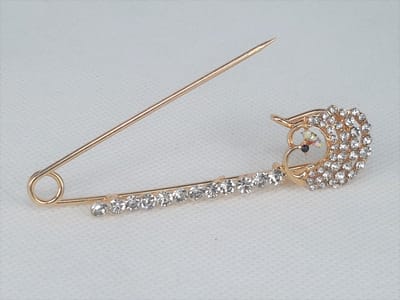 Speld, goudkleurig metaal, langwerpig, strass op een pin en strass steentjes op ronding van een pauw