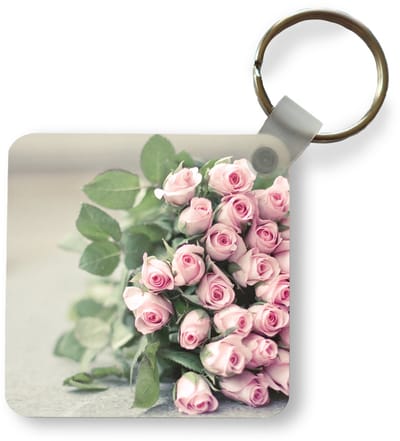 Sleutelhanger - Uitdeelcadeautjes - Een grote boek van roze rozen ligt op een tafel. - Plastic