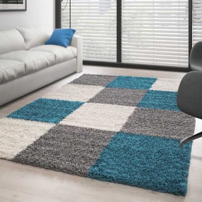 Hoogpolig vloerkleed met een turquoise-wit-grijs geblokt patroon. 80x150 cm