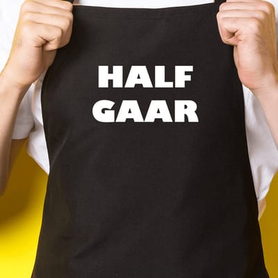 Zwart keukenschort / BBQ-schort met tekst | Half gaar | Katoen - One size - Verstelbaar - Wasbaar - Cadeau voor hem - Vaderdag - Gratis verzending - Cadeau voor Kerst & sinterklaas | Incl. 2 jaar garantie