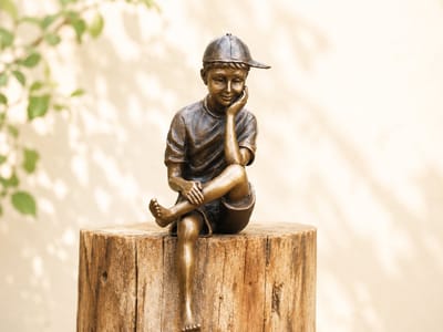 Tuinbeeld - bronzen beeld - Zittende jongen met pet - Bronzartes - 19 cm hoog