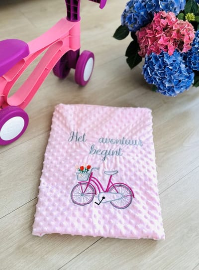 Roze babydeken met een fiets en een geborduurde toewijding in het Nederlands/Pink baby blanket with a bicycle and dedication in Dutch embroidered 95 x 120 cm