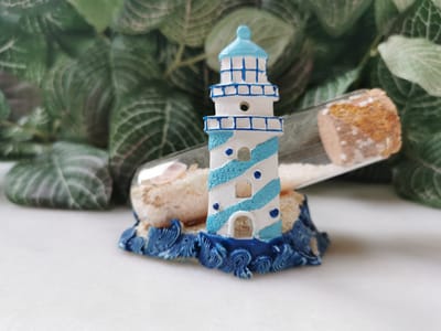 Beeldje Vuurtoren blauw met golven en flesje met zand en schelpjes 10cmBx7.5cmHx4.5cmD