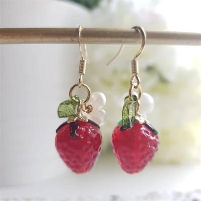 Une paire de boucles d'oreilles pendantes en verre en forme de fraise rouge beige
