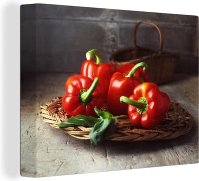 Canvas Schilderij Vier rode paprika's op een rieten mand - 120x90 cm - Wanddecoratie