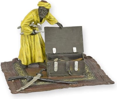 EEN BRONZEN BEELD VAN EEN ARABIER OP EEN TAPIJT MET WAPENKIST