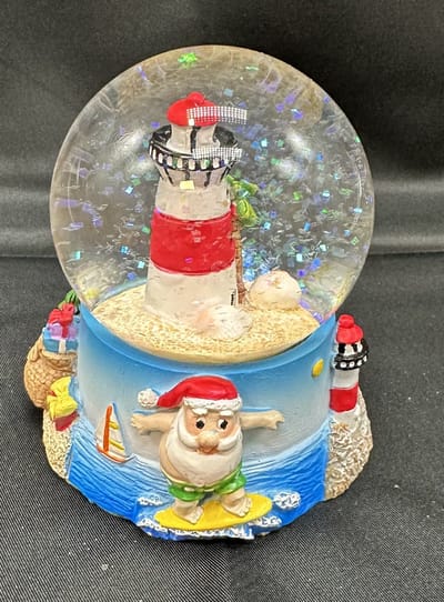 Glitterbol met tropische Kerstman + vuurtoren - Meerkleurig - Hoogte 9 x dia 7 x 8 cm - Polyresin + Glazen bol - Kerstdecoratie - Kerstversiering - Woonaccessoires