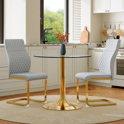 Tafel- en stoelenset: Ronde glazen tafel met een diameter van 85 cm in een ietwat luxueuze stijl, ondersteund door goudkleurige metalen poten. Gecombineerd met twee moderne eetkamerstoelen in lichtgrijs en goud.