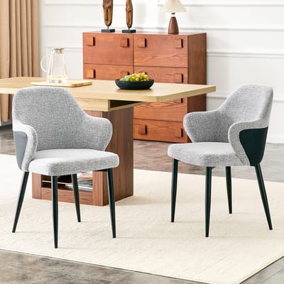 Set van 2 grijze stoffen eetkamerstoelen. Hoogte 83 cm, rugleuning met een contrasterende combinatie van grijze stof en zwart PU-leer, kruisvormige metalen steunpoten voor extra stevigheid.