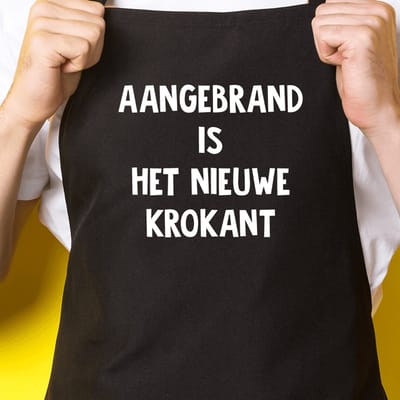 Zwart keukenschort / BBQ-schort met tekst | Aangebrand is het nieuwe krokant | Katoen - One size - Verstelbaar - Wasbaar - Cadeau voor hem - Vaderdag - Gratis verzending - Cadeau voor Kerst & sinterklaas | Incl. 2 jaar garantie