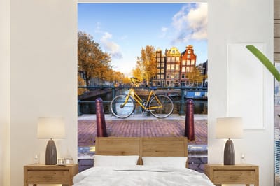 Behang - Fotobehang Fiets voor de gracht met uitzicht op Amsterdamse architectuur - Breedte 160 cm x hoogte 240 cm