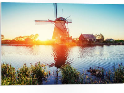 WallClassics - PVC Schuimplaat - Zonlicht langs Hollandse Molen aan het Water - 75x50 cm Foto op PVC Schuimplaat (Met Ophangsysteem)