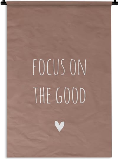 Wandkleed - Wanddoek - Engelse quote "Focus on the good" met een hartje op een bruine achtergrond - 60x90 cm - Wandtapijt