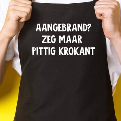 Zwart keukenschort / BBQ-schort met tekst | Aangebrand? Zeg maar pittig krokant | Katoen - One size - Verstelbaar - Wasbaar - Cadeau voor hem - Vaderdag - Gratis verzending - Cadeau voor Kerst & sinterklaas | Incl. 2 jaar garantie