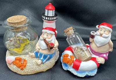 Tropische Kerstman met Vuurtoren en Zwemband + zand in glazen fles - Set van 2 stuks - Polyresin - hoogte 9 x 8 x 7 cm - Kerstdecoratie - Woondecoratie - Woonaccessoires
