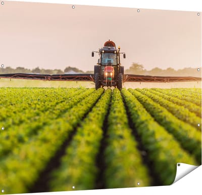 Gards Tuinposter Rode Tractor op het Veld aan het Sproeien - 150x120 cm - Tuindoek - Tuindecoratie - Wanddecoratie buiten - Tuinschilderij