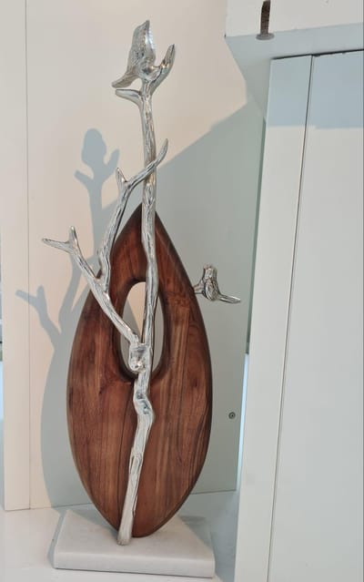 Sculptuur vogels op een tak van aluminium en mangohout op een wit marmeren voet