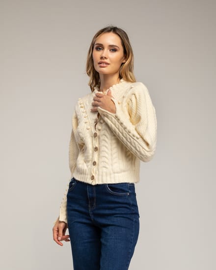 Gehaakt vest met pompons en bloemendetails.