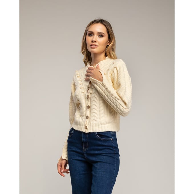 Gehaakt vest met pompons en bloemendetails.