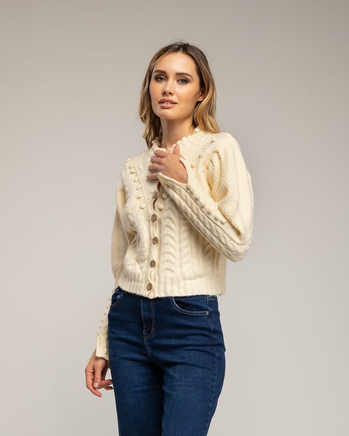 Gehaakt vest met pompons en bloemendetails.