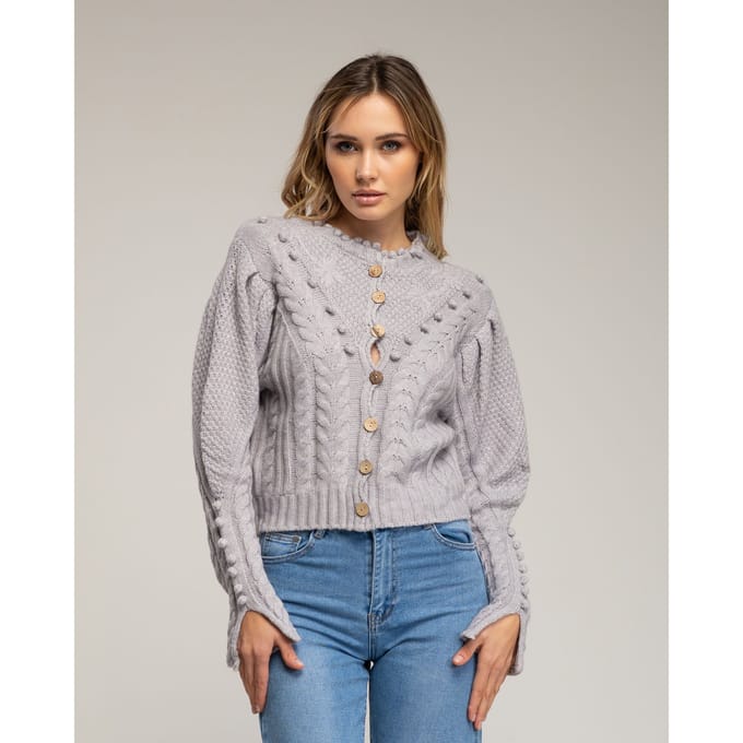Gehaakt vest met pompons en bloemendetails.